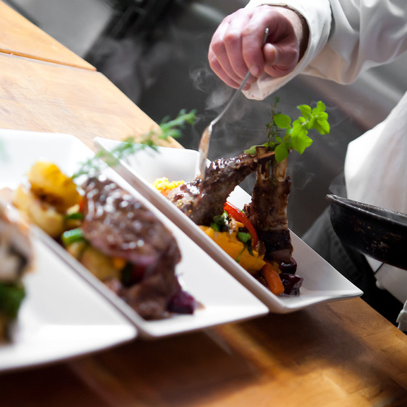 a chef plating three dishes with gourmet food