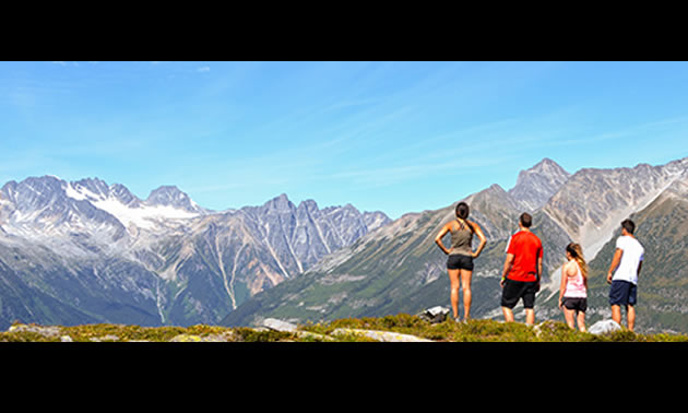 Group of people standing on mountain admiring the distant view. 