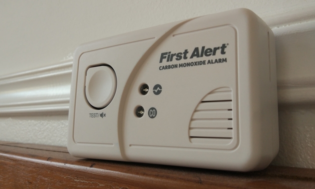 A white carbon monoxide detector sitting on a ledge