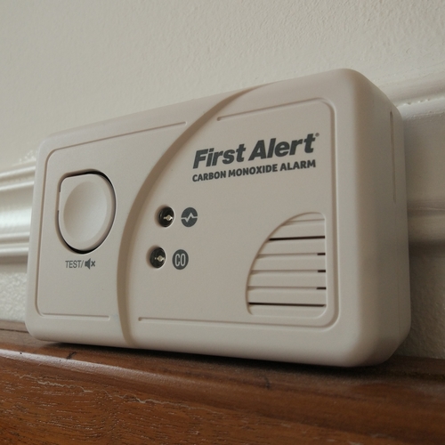 A white carbon monoxide detector sitting on a ledge