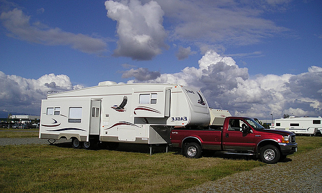 rv parked with a red truck hitched to it