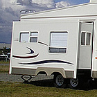 rv parked with a red truck hitched to it