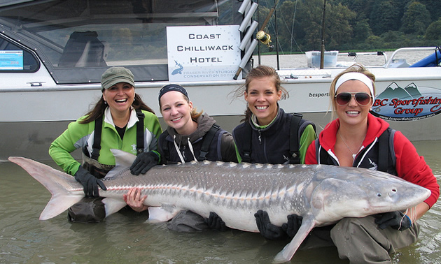 women holding onto a large fish