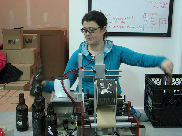 Sara Campbell labels each bottle at Left Field Cider Co.