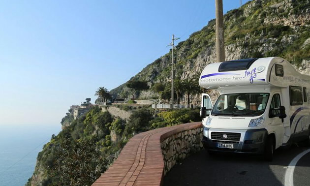 RV parked along high cliff-top road. 