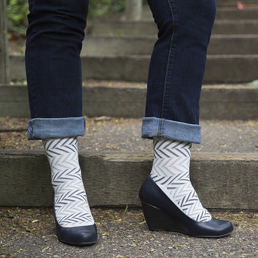 A women in rolled-up jeans, herring bone design compression socks and wedge healed shoes.