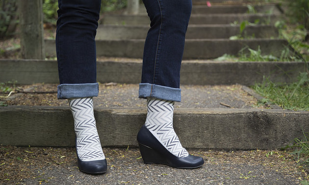 A women in rolled-up jeans, herring bone design compression socks and wedge healed shoes.