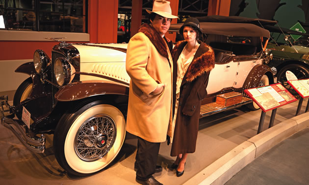 classic car with two people standing in '20s attire