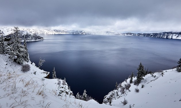 Crater lake with snowy trees and mist all around it