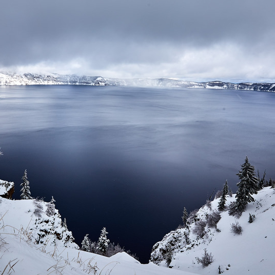 Crater lake with snowy trees and mist all around it