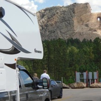 A side view of a truck and camper, with  Crazy Horse Memorial, Black Hill South Dakota, USA in the background. 