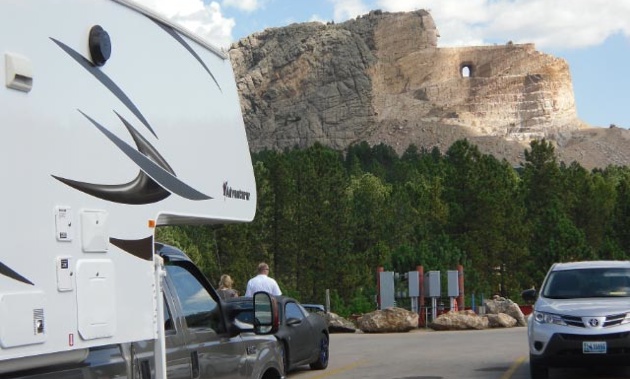 A side view of a truck and camper, with  Crazy Horse Memorial, Black Hill South Dakota, USA in the background. 