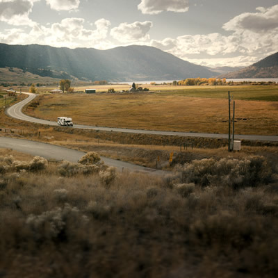 A camper is travelling on a winding rural road.