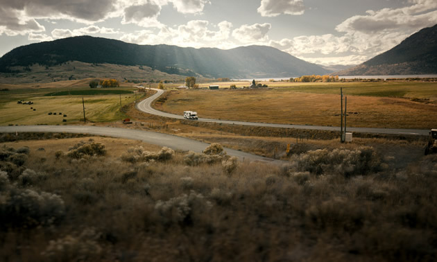 A camper is travelling on a winding rural road.