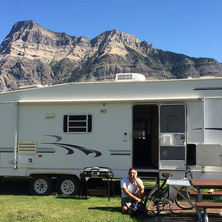 Dave Sonnenberg crouching outside of his RV which is parked at Waterton Natioal Park
