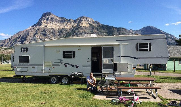 Dave Sonnenberg crouching outside of his RV which is parked at Waterton Natioal Park