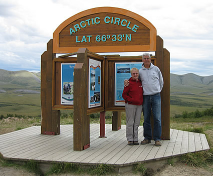 Husband and wife standing in front of an Arctic Circle sign