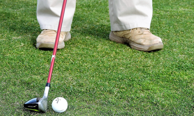 A man holding a golf club - about to hit the ball