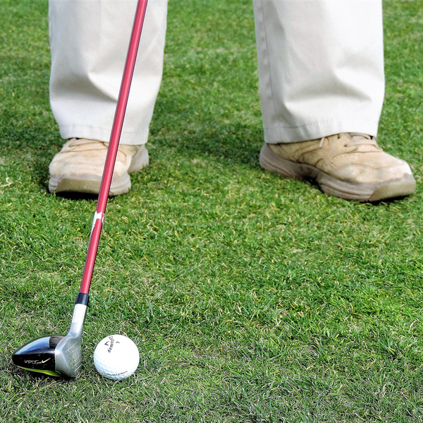 A man holding a golf club - about to hit the ball