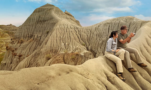 Two people sitting on rock formations at Dinosaur Provincial Park in Alberta.