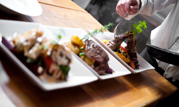 The chef putting the finishing touches on three plates at the Angler's Dining Room. 