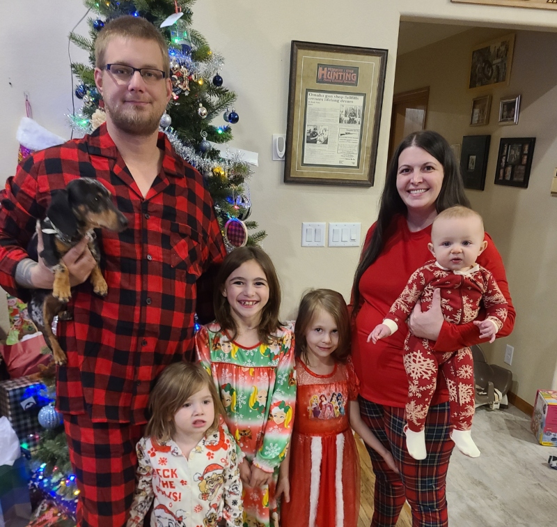 A family of six dressed in matching red plaid Christmas outfits