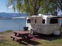 Picture of an Escape trailer set up next to a picnic table. 