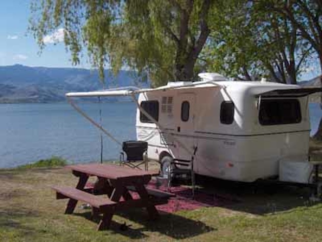 Picture of an Escape trailer set up next to a picnic table.