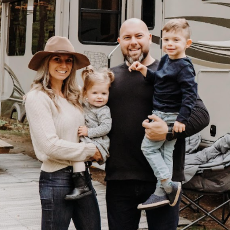 A lady and man with their two children in front of their RV