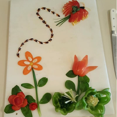 A tray of vegetables cut into a flower scene. 