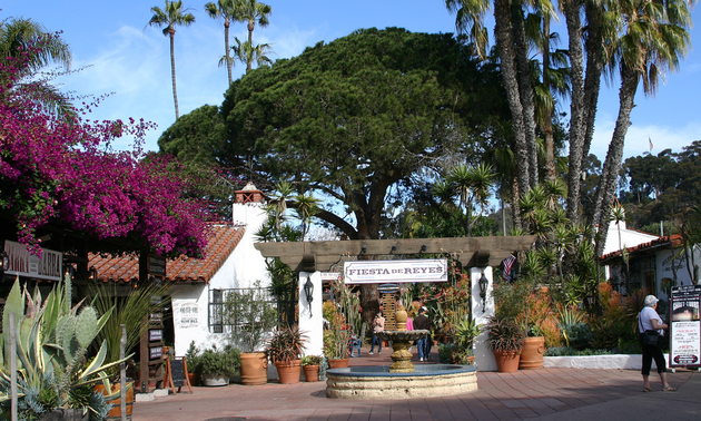 entrance to a resort with trees on either side