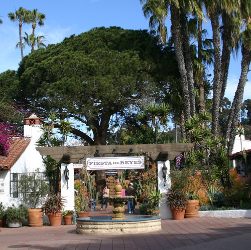 entrance to a resort with trees on either side