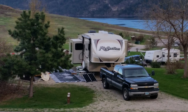 Shown is a campground in Fintry Provincial Park with a truck and fifth wheel parked.