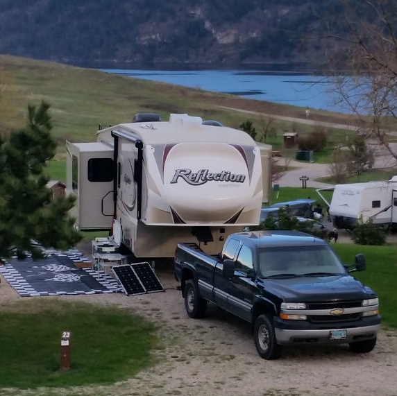 Shown is a campground in Fintry Provincial Park with a truck and fifth wheel parked.