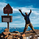 Man standing on a mountain peak with his arms raised