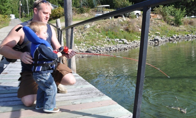 Gavin Johnson, fishing with his daddy, has a fish on his line.