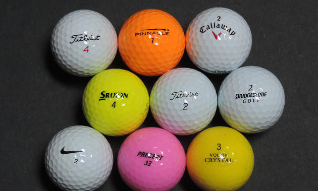 A selection of 9 golf balls of different colours, makes and sizes.