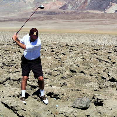 Golfer trying to hit ball in the midst of a field of rocks. 
