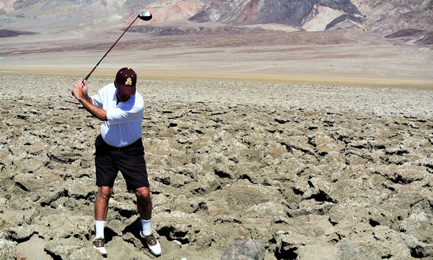 Golfer trying to hit ball in the midst of a field of rocks. 