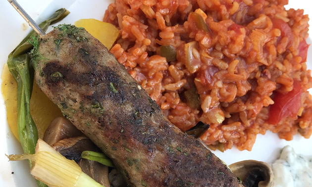 Plate with grilled sausage, vegetables and tomato rice.
