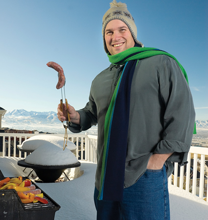 Man holding a barbecued hot dog on a stick