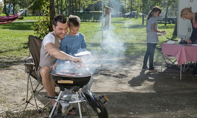 A father teaching his young son how to barbeque.