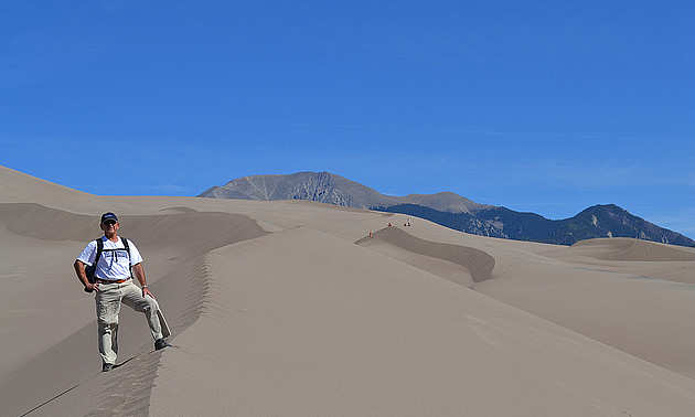 man standing by the sand dunes