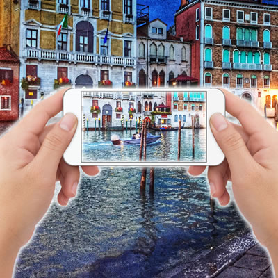 Pair of hands holding iphone with Venice canals in background. 