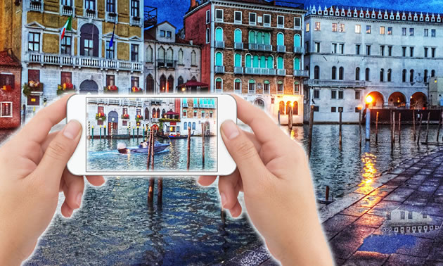 Pair of hands holding iphone with Venice canals in background. 