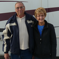 Senior couple stand with a large Everest RV behind them