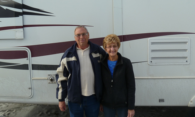 Senior couple stand with a large Everest RV behind them