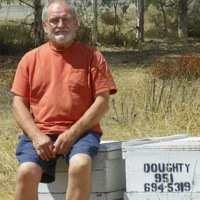 John Doughty sitting on some boxes of honey from his bees.