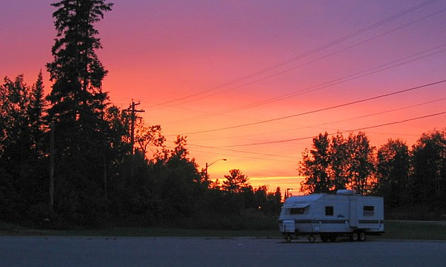 RV parked in a campsite with sunset in background