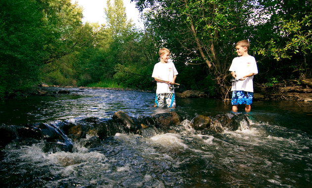 two boys fishing in a creek